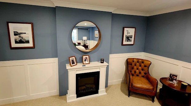 Round mirror and two framed black-and-white photographs hung level on a blue living room wall