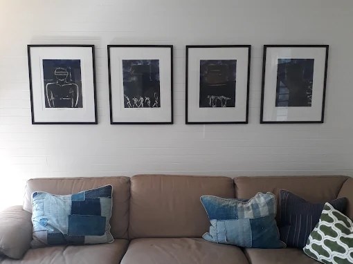 Four framed prints hung in an evenly spaced row above a sofa